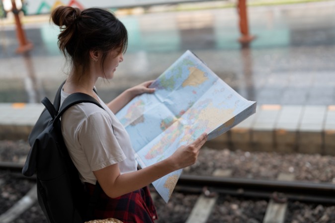 Joven con mochila leyendo un mapa en una estación de tren